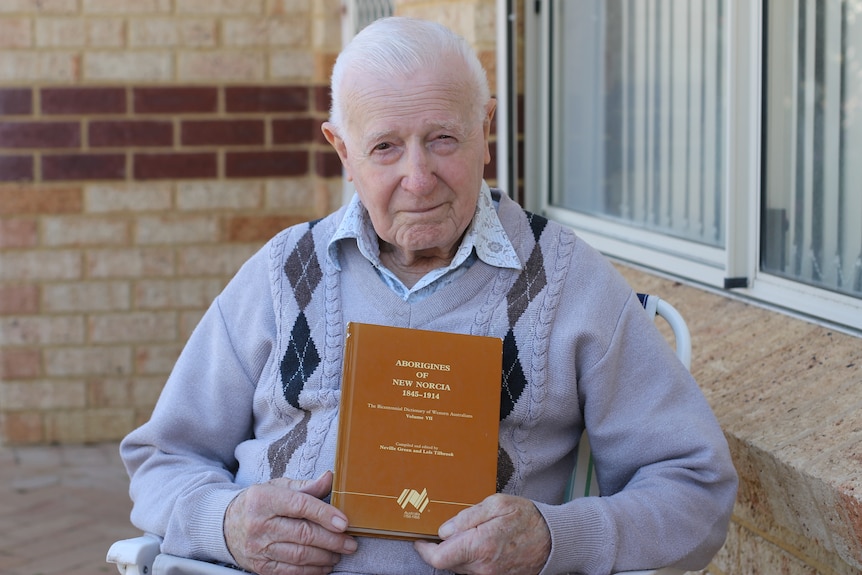 man is sitting facing the camera, holding his book