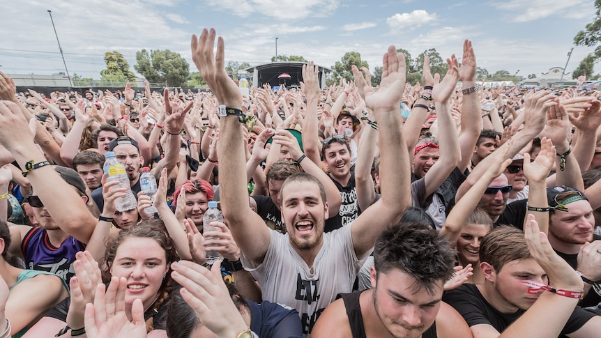 A crowd of young people with their hands in the air