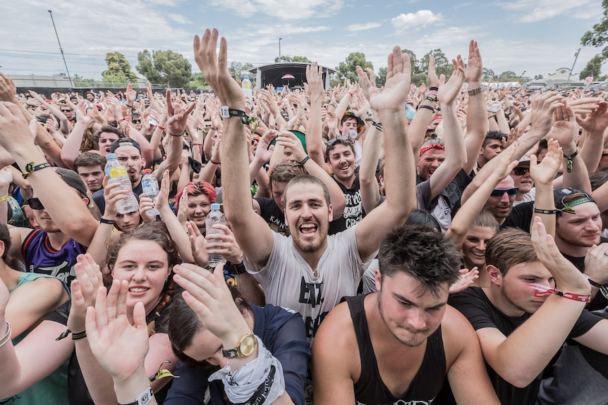 A crowd of young people with their hands in the air