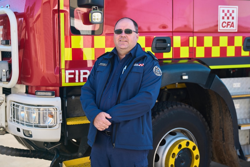 A CFA captain stands in front of a fire truck.