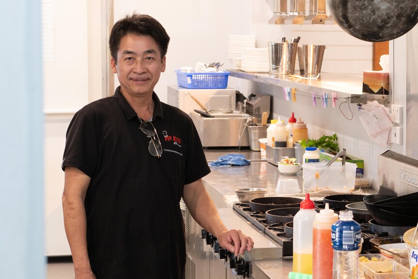 A middle-aged man stands in a commercial kitchen.