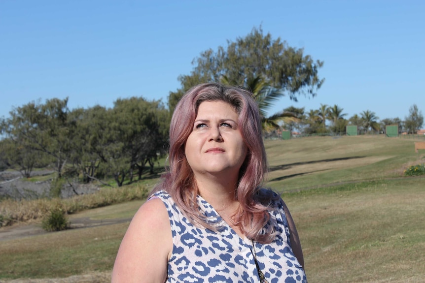 A woman stands outside looking up at the sky