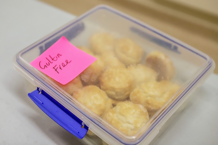 A tupperware container with 20 scones inside and a pink post-it note that reads Gultin Free 