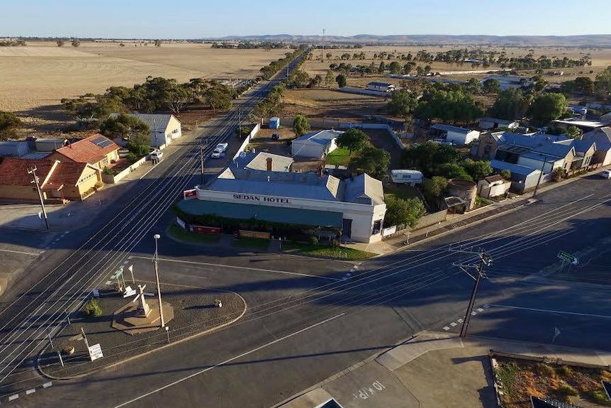 An aerial shot of the Sedan Hotel in the centre of a tiny town. The surrounding earth is barren and dry.