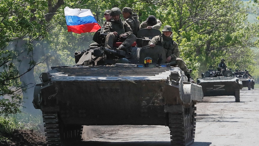 Pro-Russian soldiers sit atop a tank with Russian flag flying.