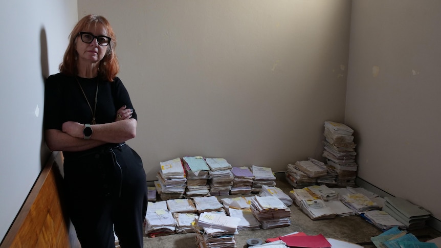 A woman with her arms folded in front of lots of wet legal documents 