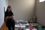 A woman with her arms folded in front of lots of wet legal documents 