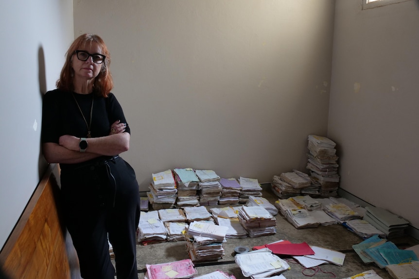 A woman with her arms folded in front of lots of wet legal documents 