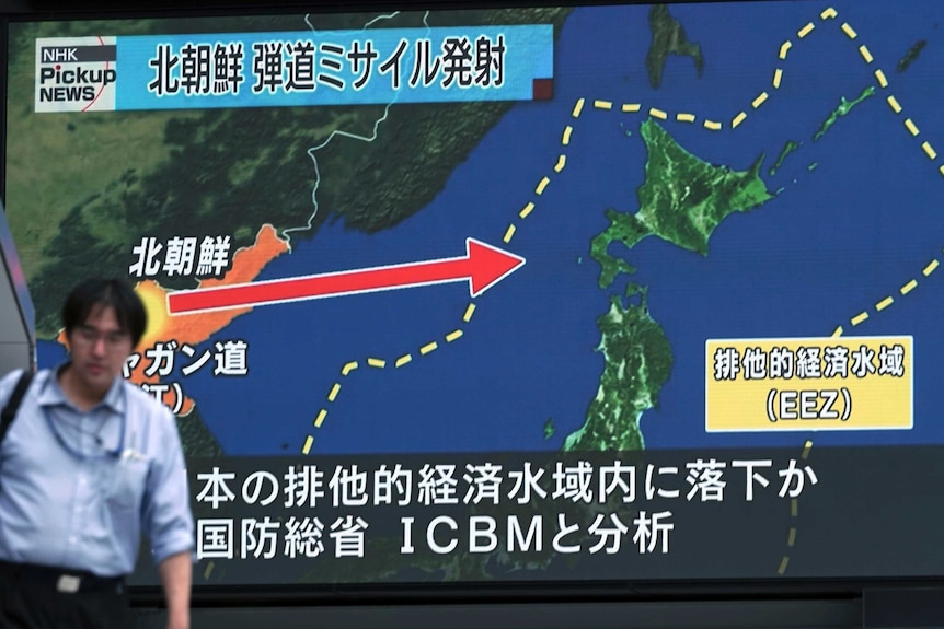A man walks in front of a map showing the route of North Korea's missile launch.