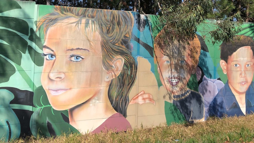 Street art of young girl on a sound wall.