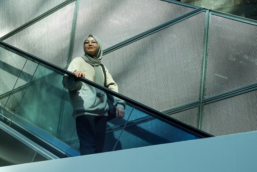 Adiba travels down an escalator in Melbourne