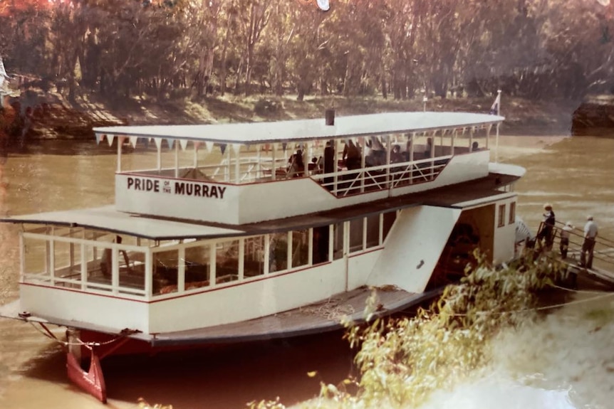 Une vieille photo de film d'un bateau blanc avec des personnes à bord en 1985.