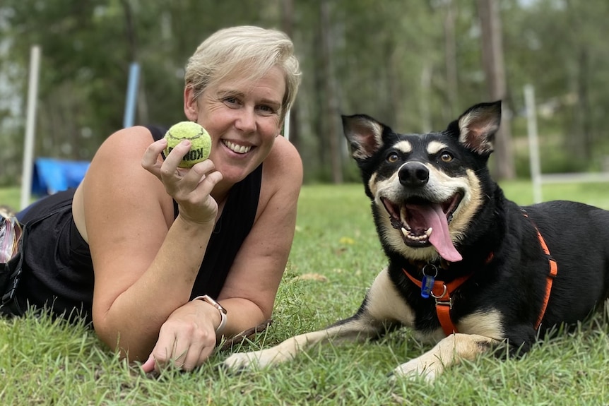woman holding a ball with her dog