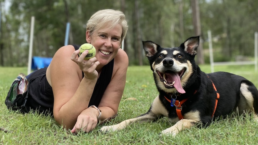 woman holding a ball with her dog