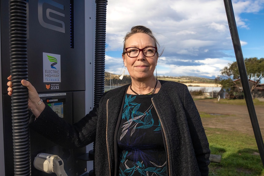 Libby Chaplin stands next to a battery recharging station, which has a sticker that says 'Electric Highway Tasmania'