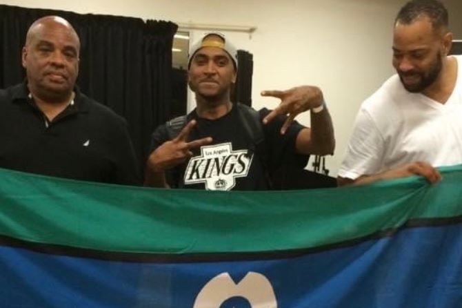 Three men stand behind the Torres Strait Island flag