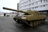 Leopard battle tank parked outside of military building.