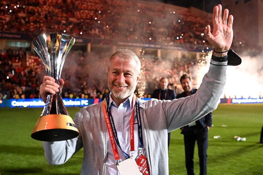 Roman Abramovich holds the Club World Cup trophy in one hand