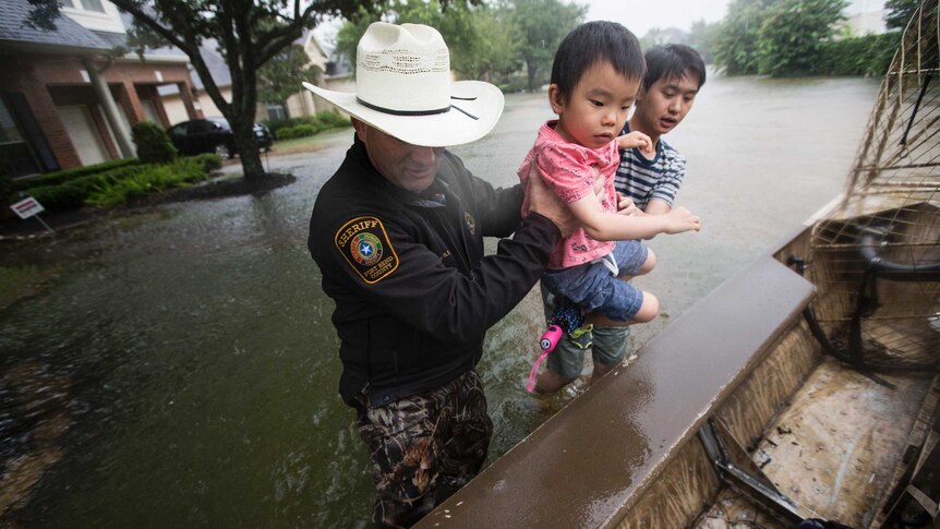 Fort Bend County Sheriff Troy Nehls helps a little girl into a boat from floodwaters