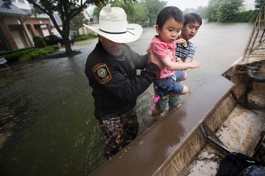 Fort Bend County Sheriff Troy Nehls helps a little girl into a boat from floodwaters
