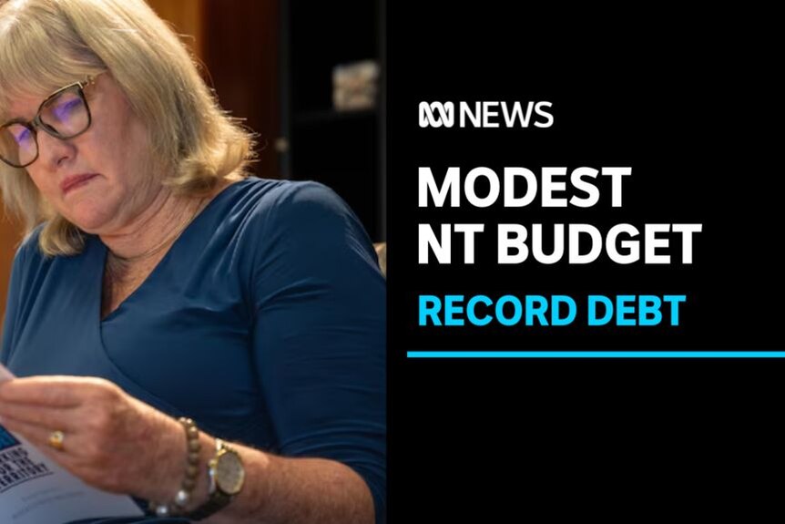 Modest NT Budget, Record Debt: NT Chief Minister wearing glasses reads a copy of the territory's budget.