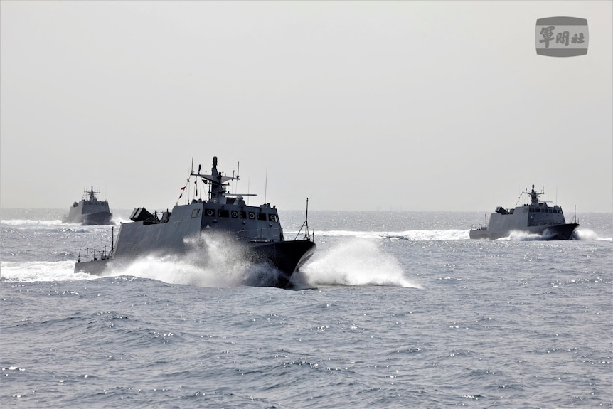 Three navy ships in the water.