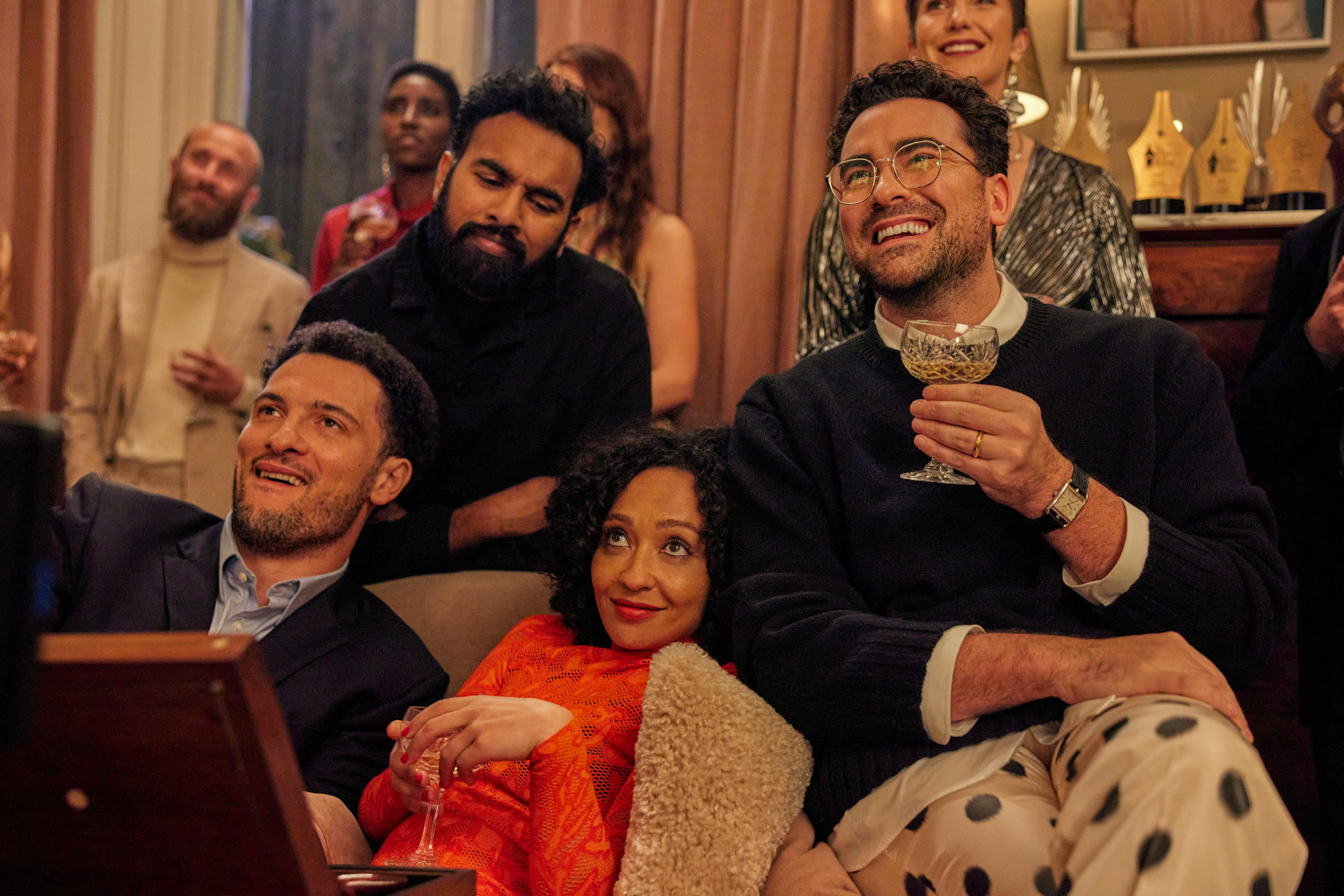 A film still of Jamael Westman, Himesh Patel, Ruth Negga and Daniel Levy, sitting close together on a couch, smiling.