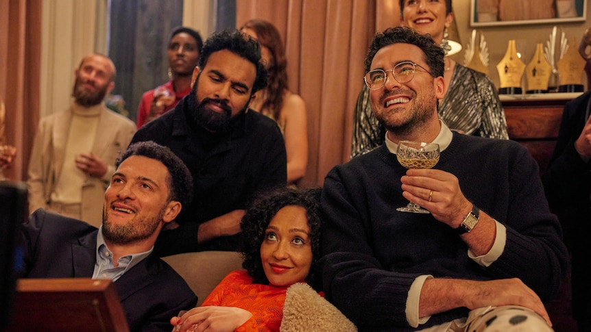 A film still of Jamael Westman, Himesh Patel, Ruth Negga and Daniel Levy, sitting close together on a couch, smiling.