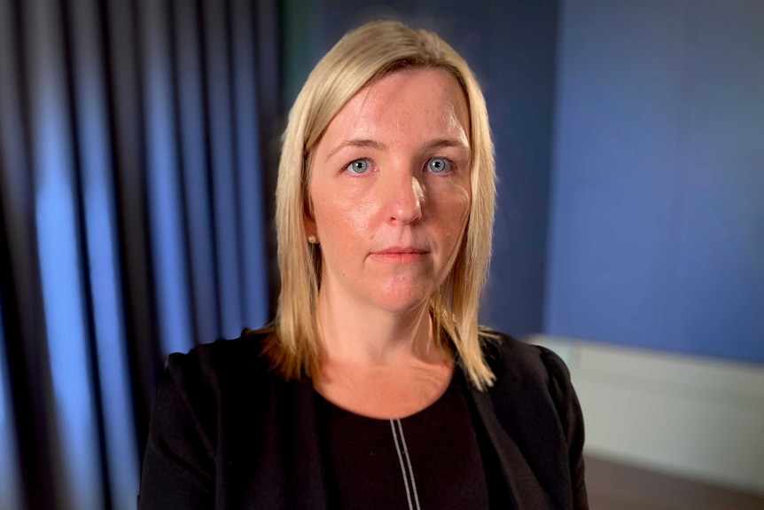 Barrister Fiona Martin looks into the camera in front of a blue backdrop.