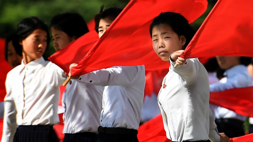 Schoolgirls practice flag-waving ahead of the seventh congress for Korea's ruling party.