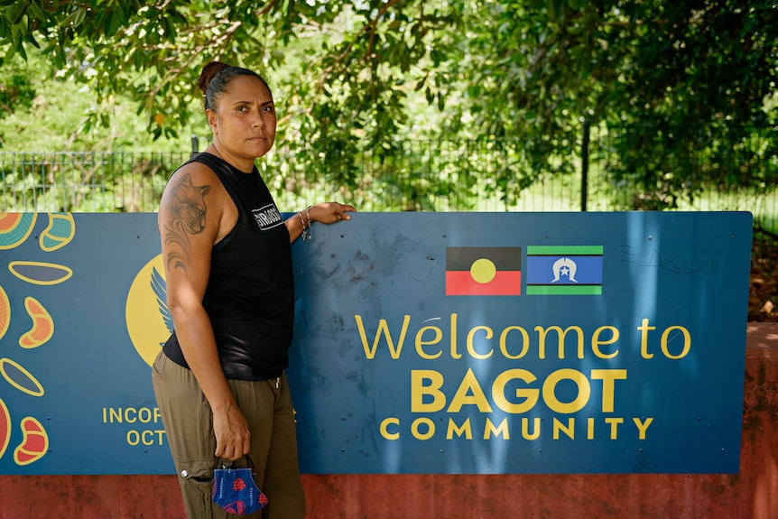 Natalie Howard looking serious and standing next to the Bagot community entrance sign, under a tree.