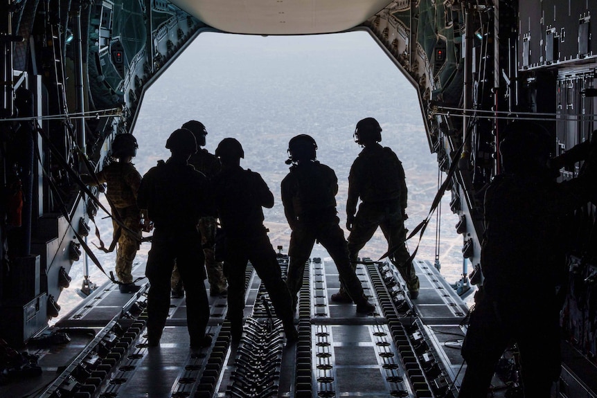 Grupa żołnierzy stojących na otwartym brzuchu samolotu 