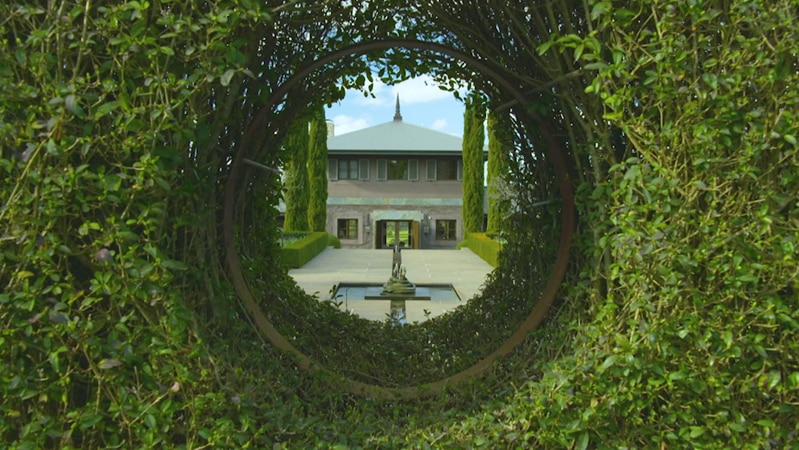 View of a grand house through a hole in a hedge