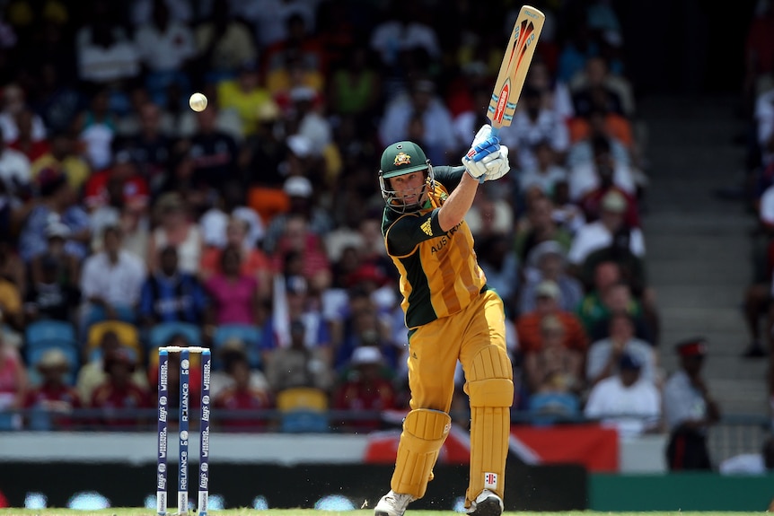 An Australian batsman hits a lofted shot on the offside during a T20 World Cup final.
