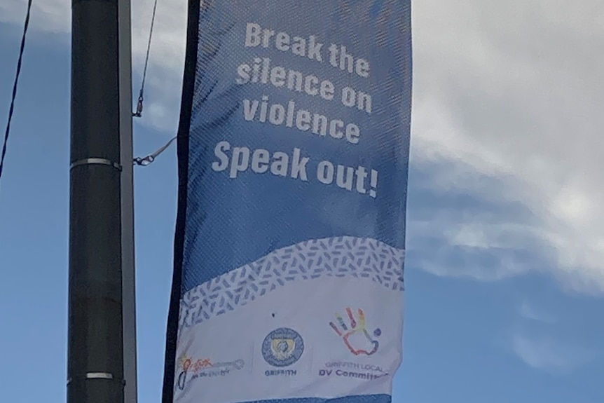 An anti-domestic violence banner hanging from a streetlight.