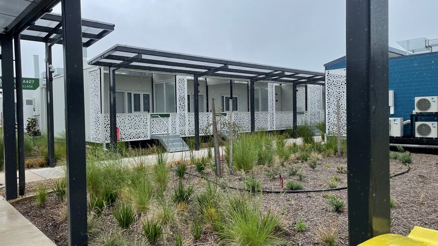 A standalone unit, clad in a decorated white facade, with a veranda and a small garden area.