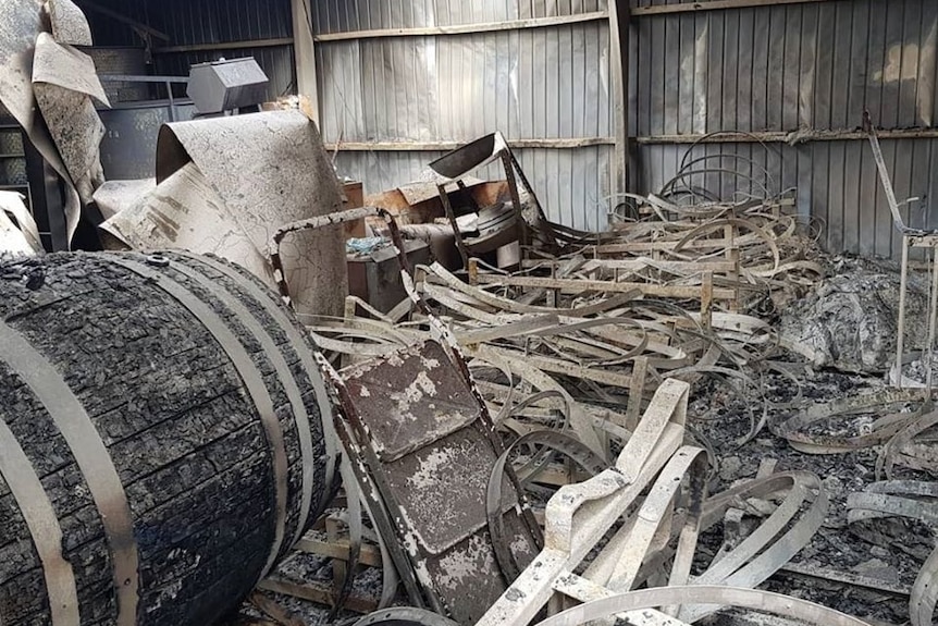 A winery shed burnt out with a barrel in the foreground