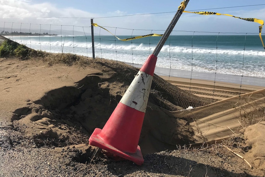 A metal stake is covered in a traffic cone where the ground has given way on the Great Ocean Road.