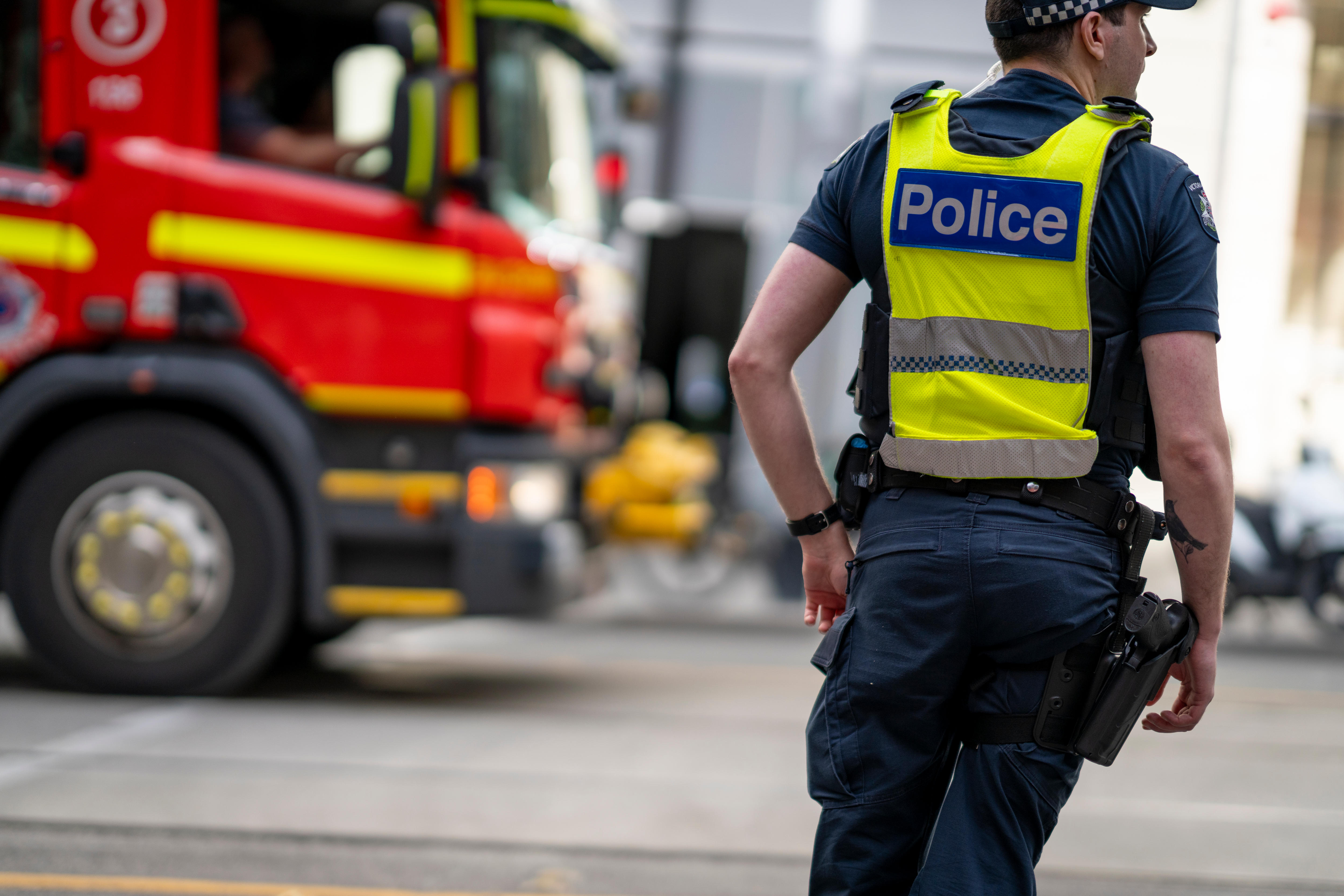 Un oficial de policía de Victoria junto a un camión de bomberos