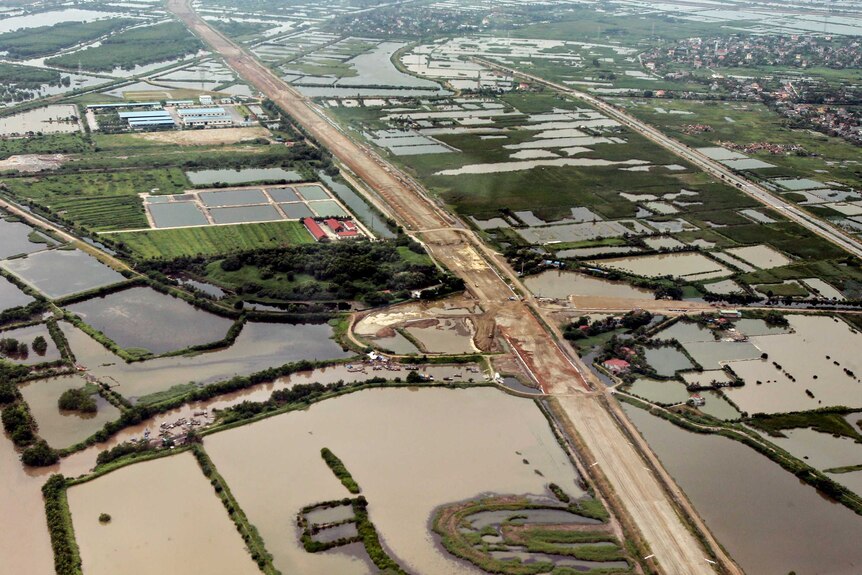 An aerial view of rice paddy fields with the city of Hai Phong in the distance.