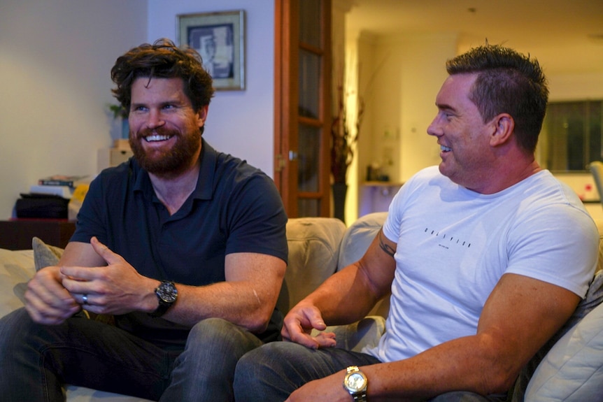 Two men sitting on a couch laughing