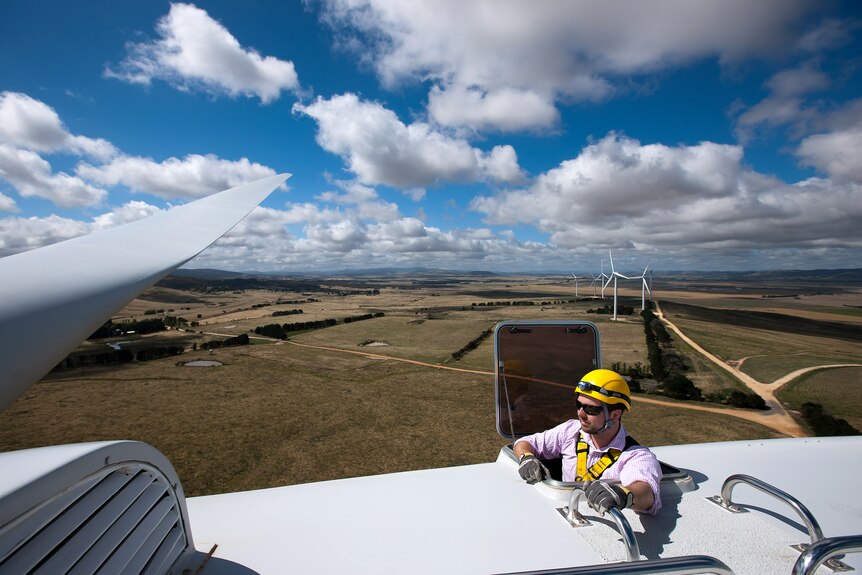 A site manager emerges at the top of a wind turbine