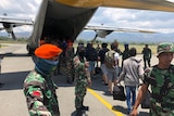 Military members usher survivors onto a plane