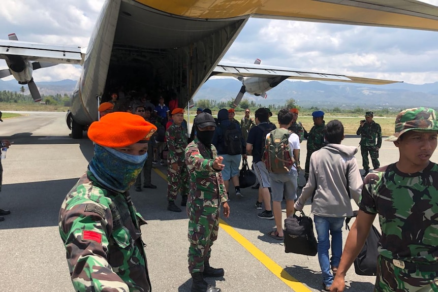 Military members usher survivors onto a plane