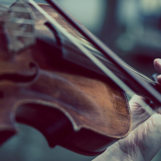 A close-up of just the body of a violin while being played.