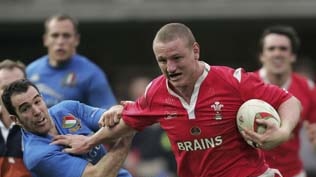 Brent Cockbain of Wales brushes aside a challenge to score the fourth try against Italy