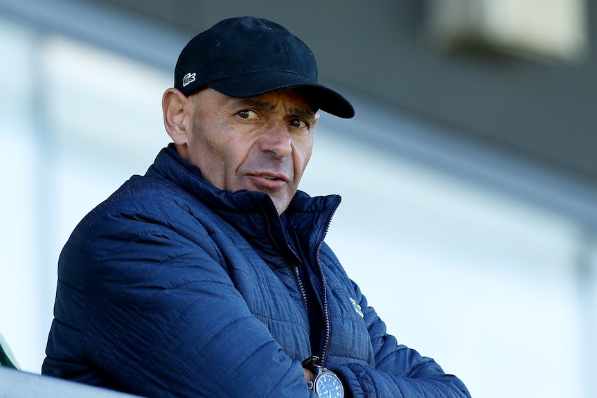 Australian tennis coach Roger Rasheed is pictured watching sport in a puffer jacket and a cap in Melbourne.