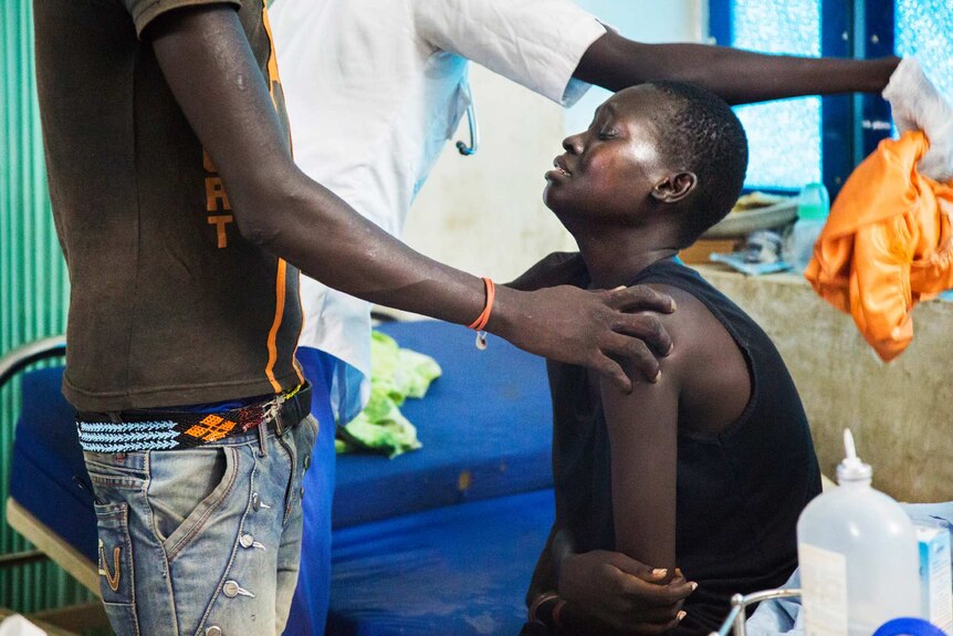 A friend of Nyamuoch puts his hand on her shoulder to comfort her in the wake of her baby's death.