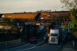 A coal train driving over a bridge with trucks driving underneath.