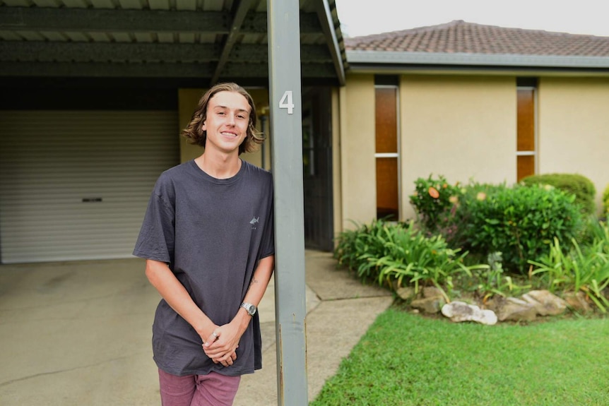 Young man standing in front of his home